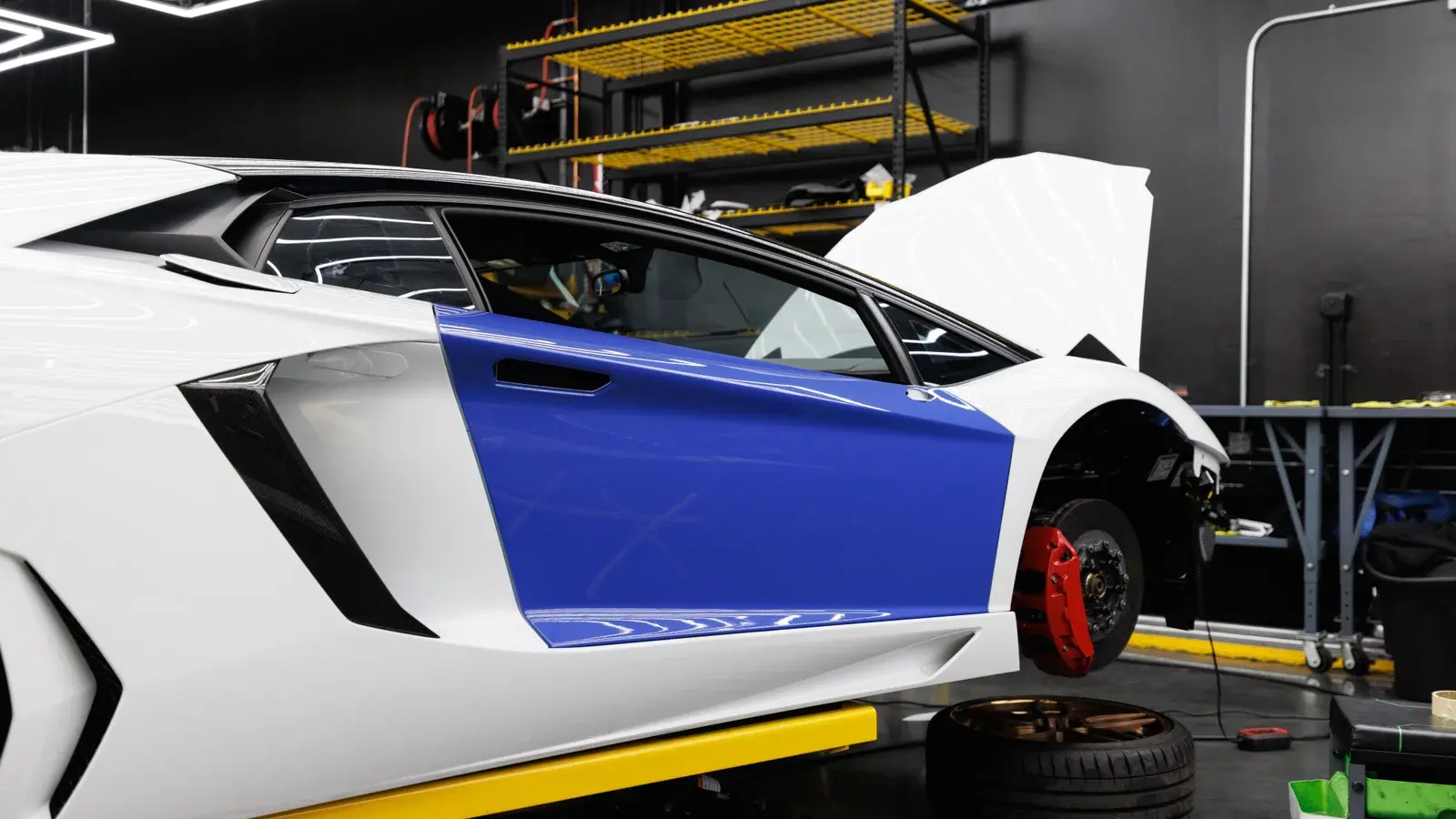 A car and a wheeled workbench inside an automotive workshop