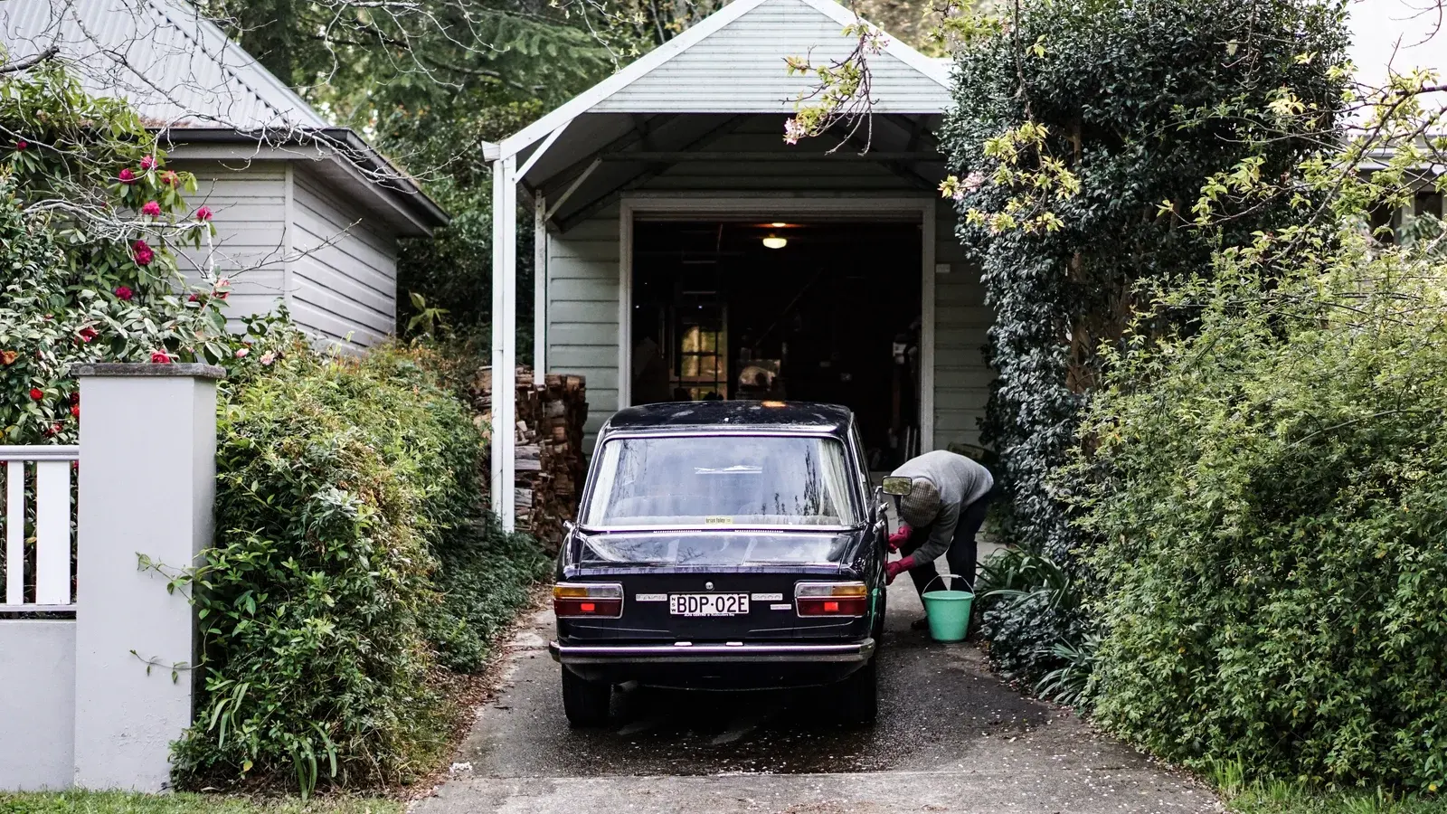 A car parked in a driveway outside a detached garage
