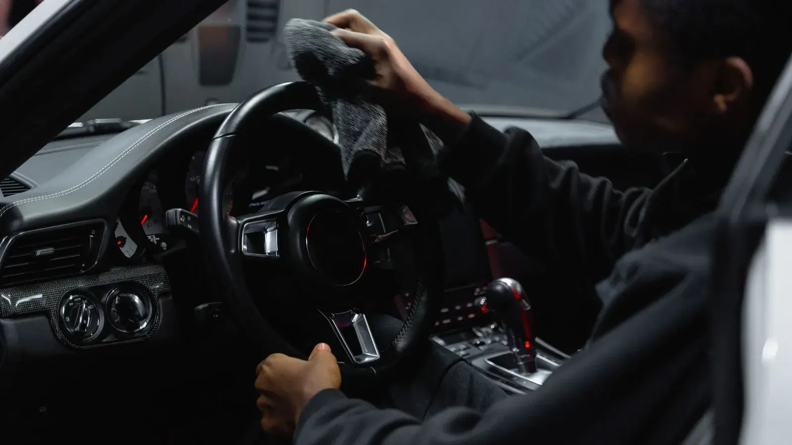 A worker wiping a car steering wheel with a microfiber cloth