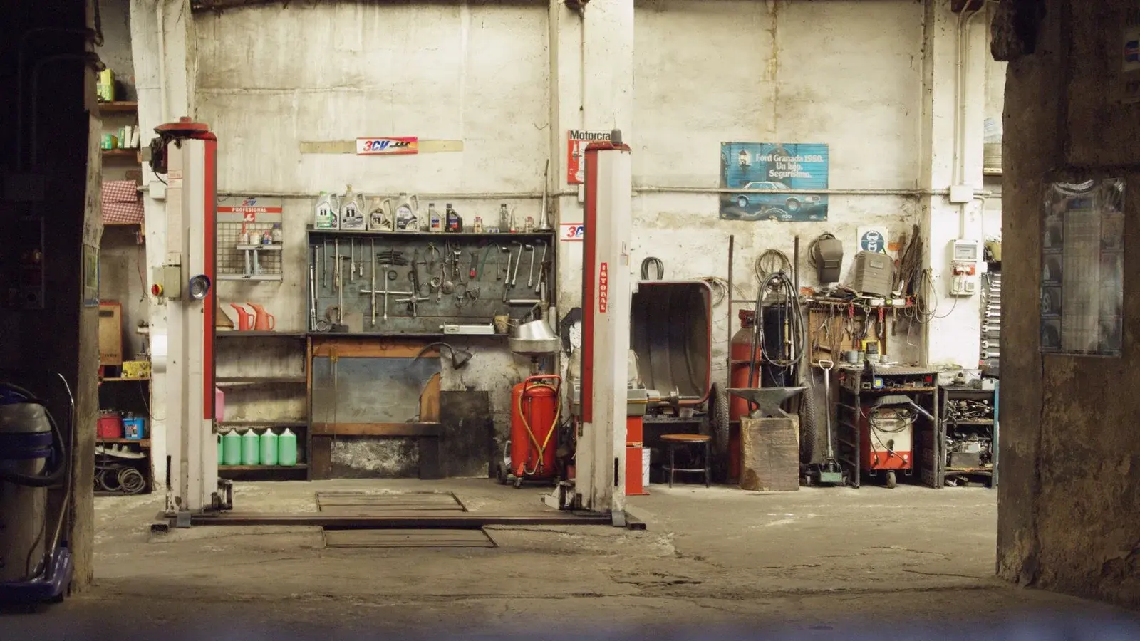 An automotive workshop with vehicle lifts, shelves, and tools