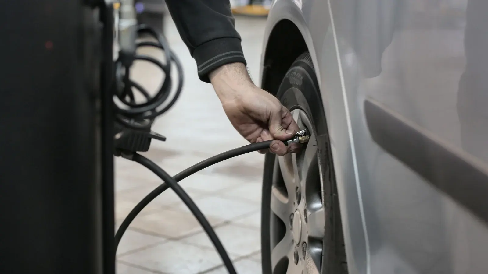 Photo by Andrea Piacquadio on Pexels A hand holding a compressed air hose chuck against a car tire valve in a repair shop.