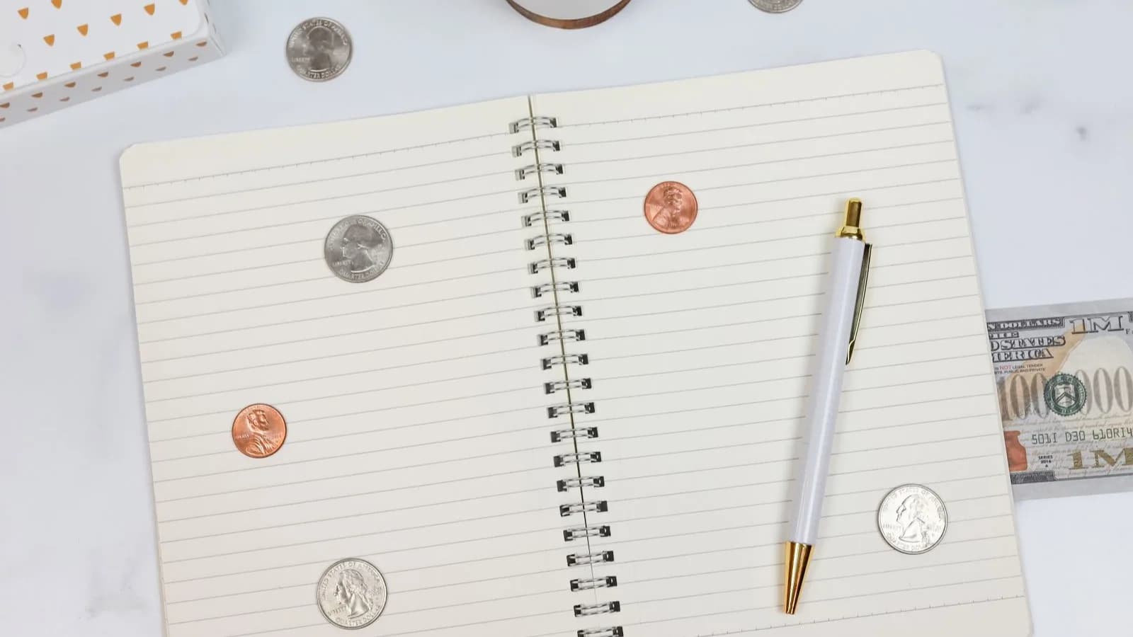 Photo by Katie Harp on Pexels An open notebook with a pen, coins, and a dollar bill.
