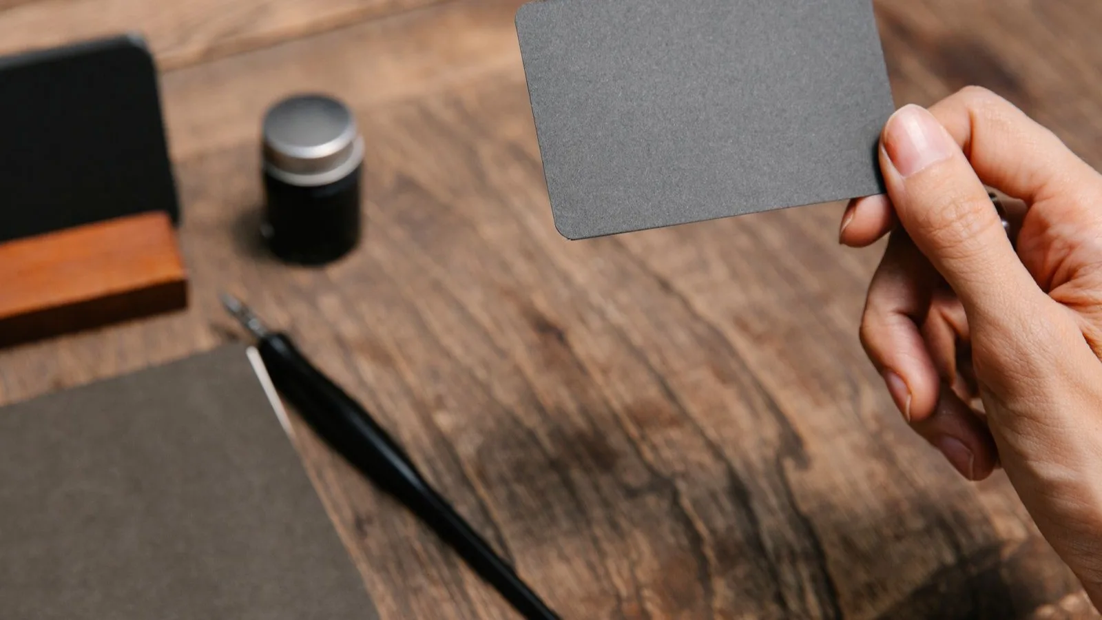 Photo by Angela Roma on Pexels A hand holding a blank business card over a desk.
