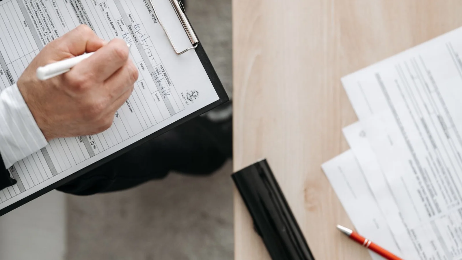 Photo by Pavel Danilyuk on Pexels A person writing on a clipboard beside paperwork.