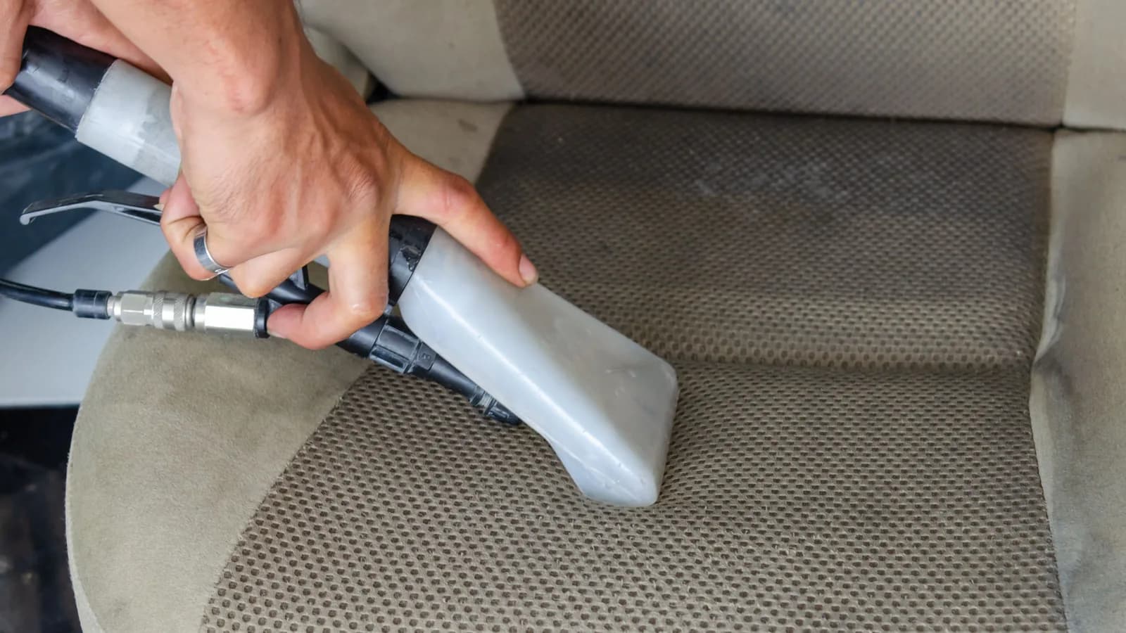 Photo by Khunkorn Laowisit on Pexels Two hands guide an upholstery extraction tool along a fabric car seat.