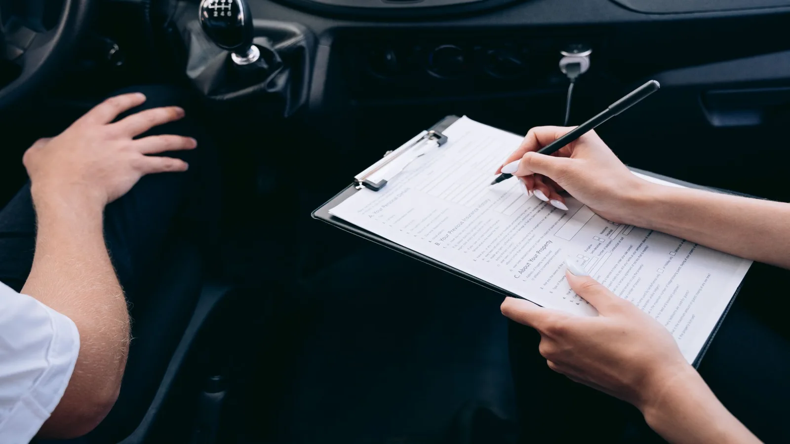 Photo by Mikhail Nilov on Pexels A person writing on a clipboard inside a car.