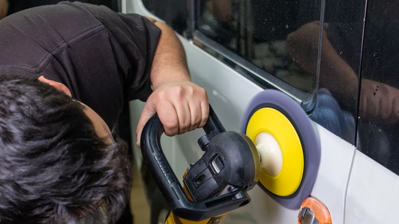 Photo by Melih Can on Pexels A worker uses a polisher on a vehicle panel in a workshop.
