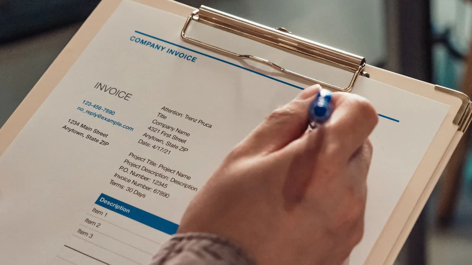 Photo by Kindel Media on Pexels A generic invoice on a clipboard with a person holding a pen.