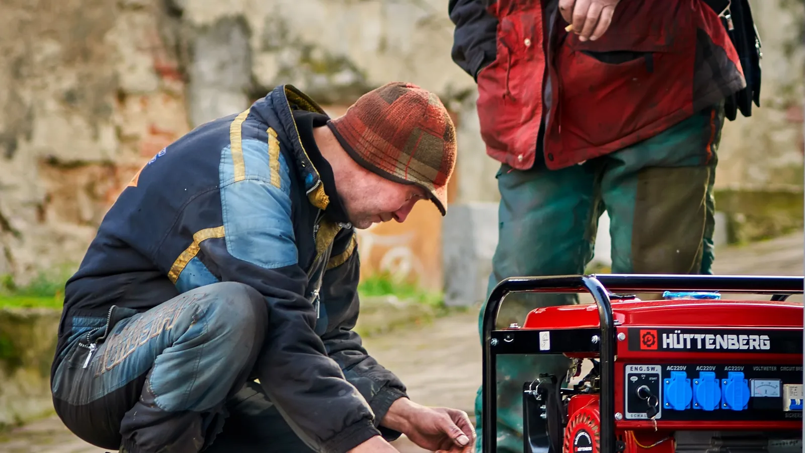 Photo by igovar igovar on Pexels Two people inspect a red portable generator outdoors.