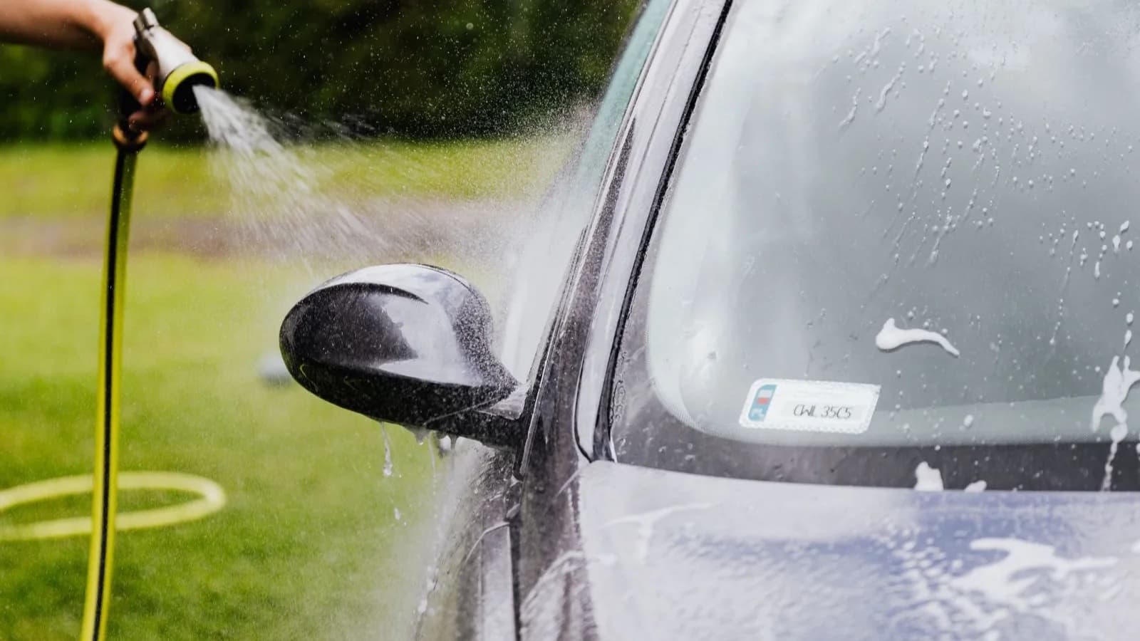 Photo by Kaboompics on Pexels A hand spraying water onto the side of a car.