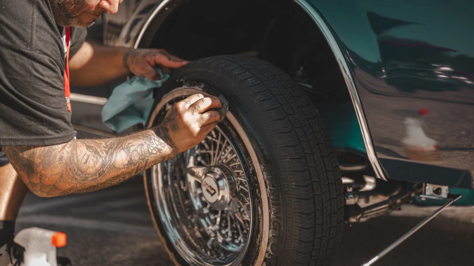 Photo by Mike Kutz on Pexels A person wiping the tire of a classic car.