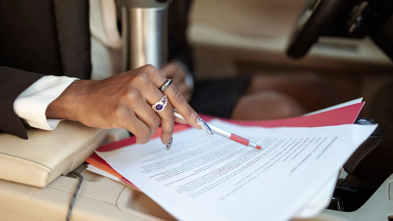 Photo by RDNE Stock project on Pexels A person reviewing papers with a pen inside a vehicle.
