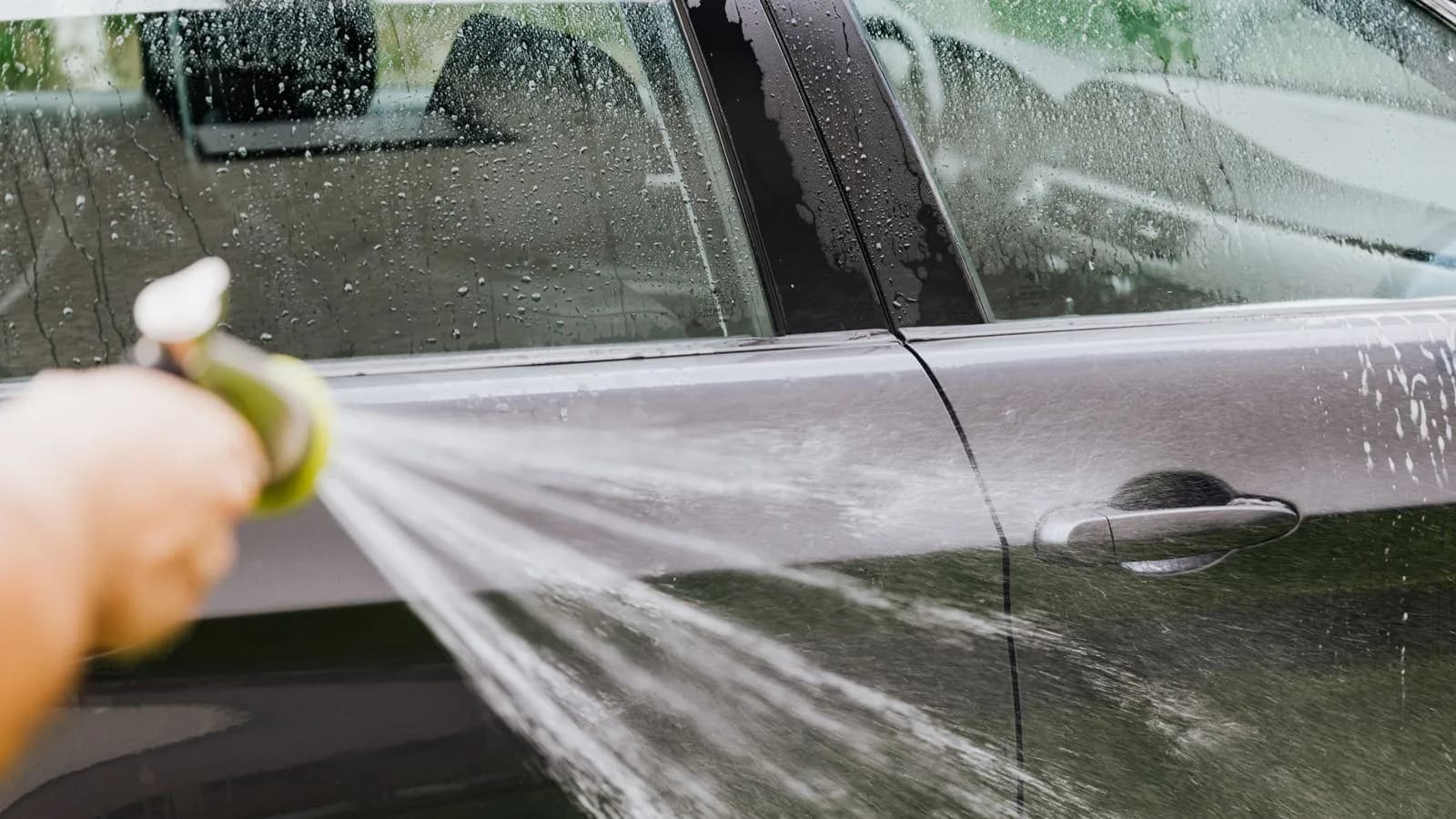 Photo by Kaboompics on Pexels Water sprays across a car door during a wash.