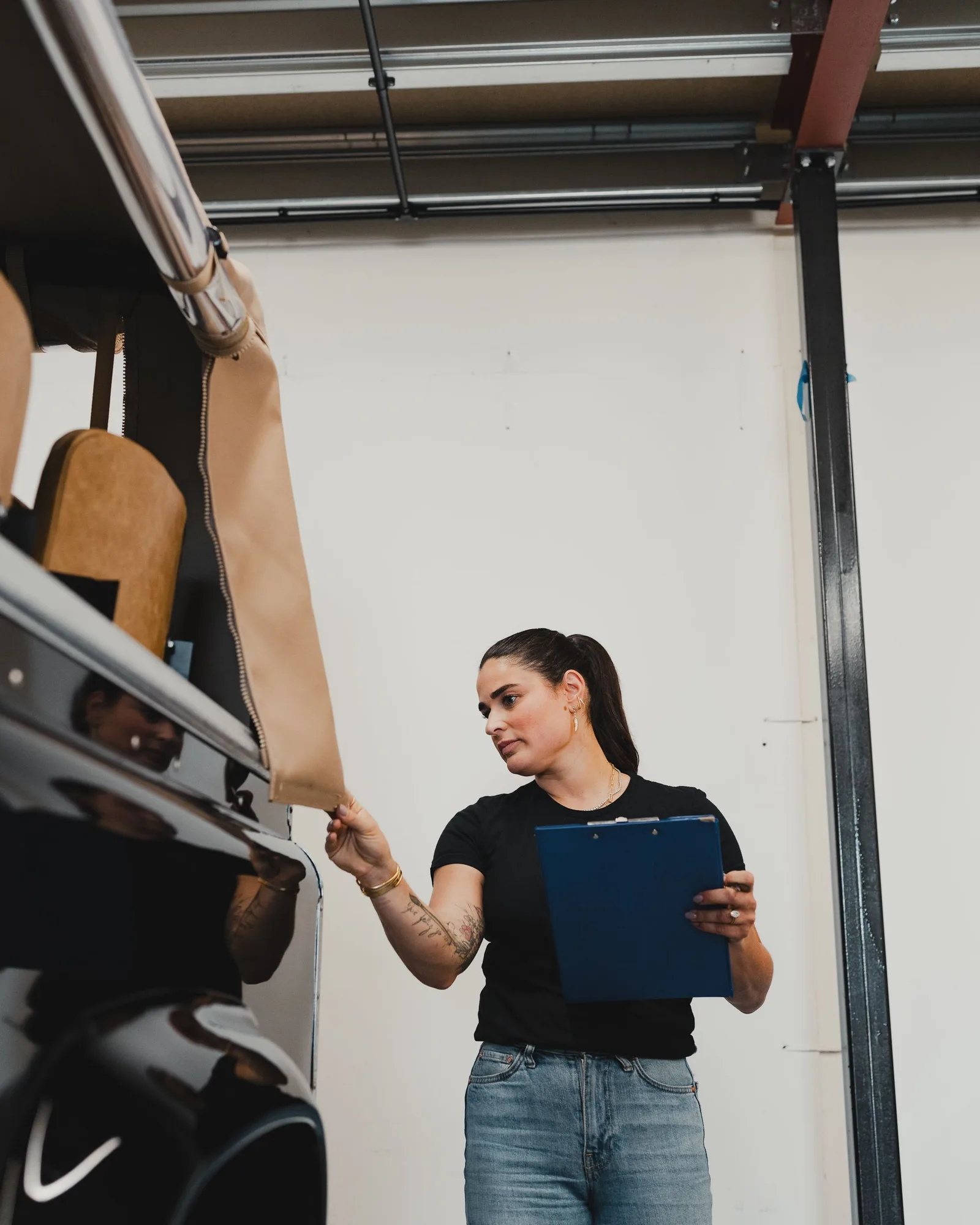 A person holding a clipboard while checking a vehicle interior.