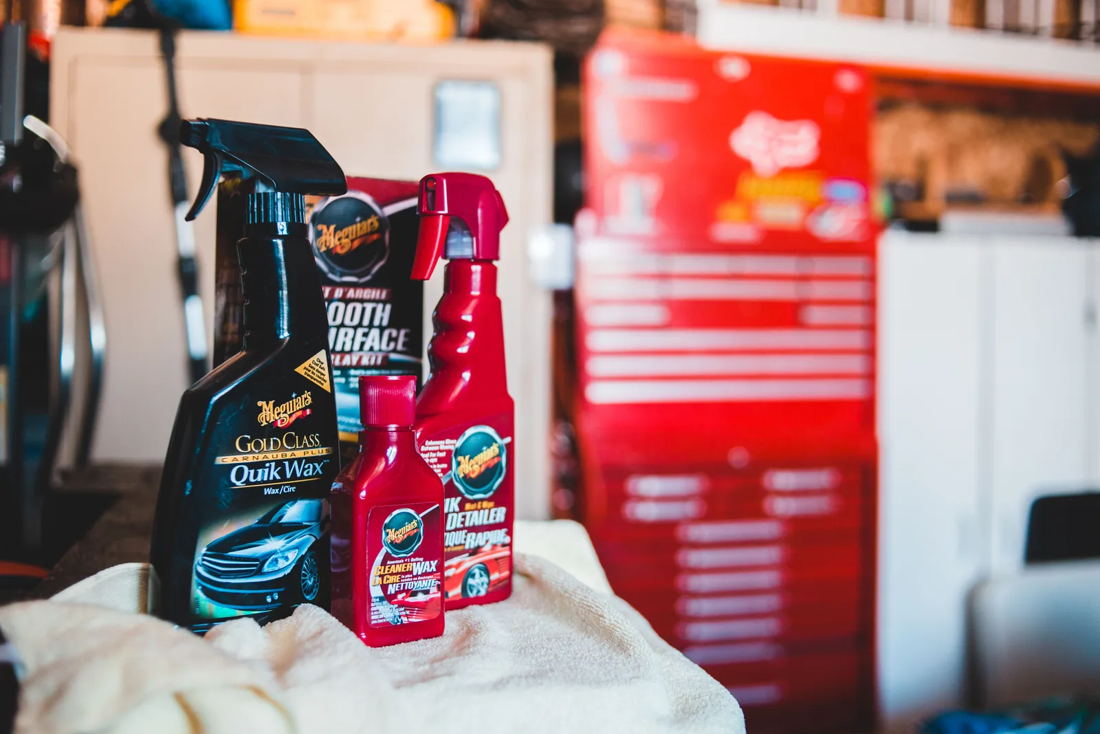 Wax and detailing spray bottles on a towel in a garage.